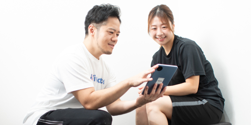 トレーナーからのトレーニング説明を受ける女性の写真